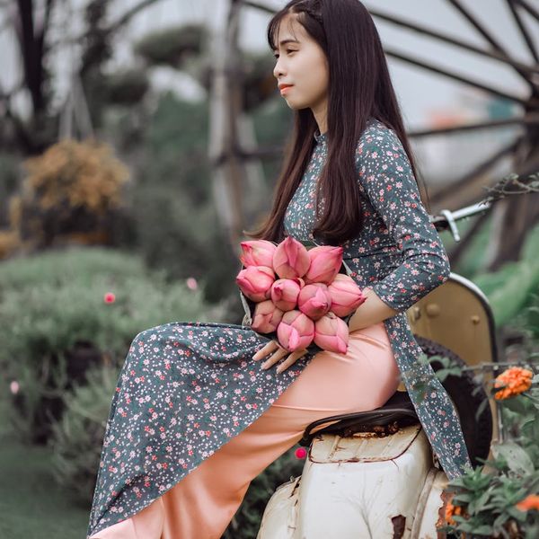 A person sitting in a lotus pose outdoors with a calm natural background.